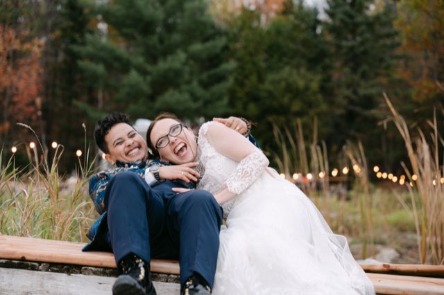 A couple laughing together on a bench at golden hour
