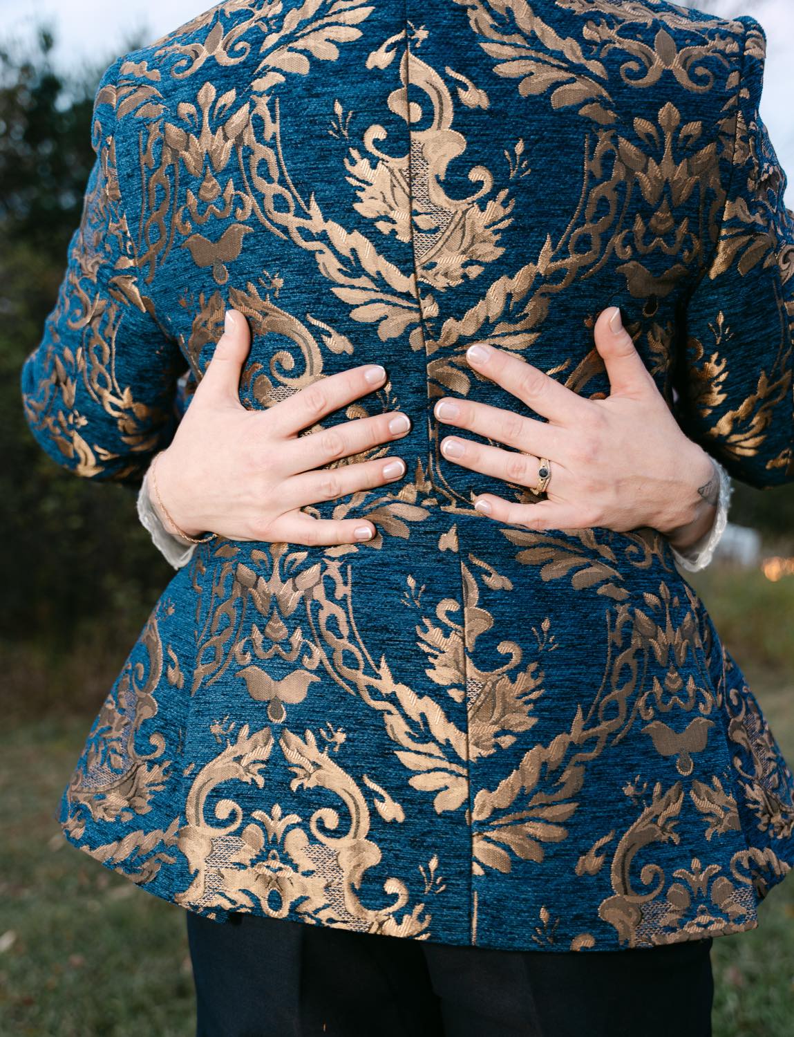 A detail of the couple’s clasped hands against gold brocade