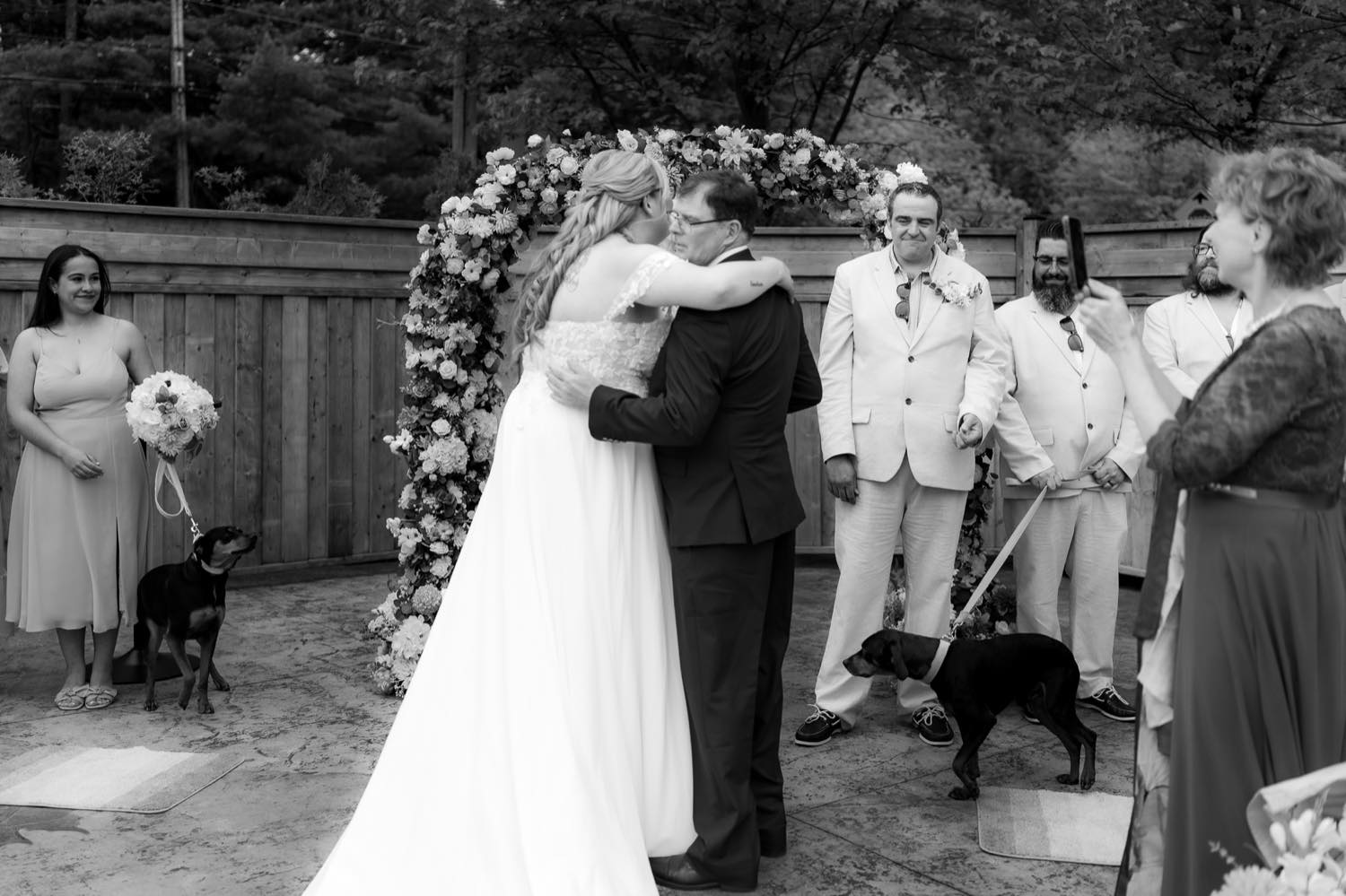A candid embrace during a wedding ceremony as guests look on